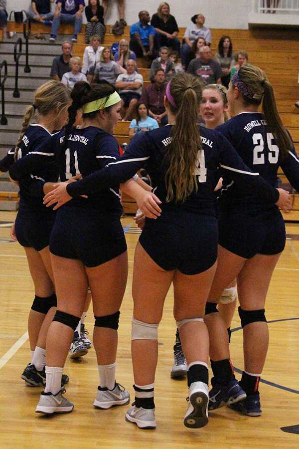 The volleyball girls bring it in for a quick group huddle between plays.