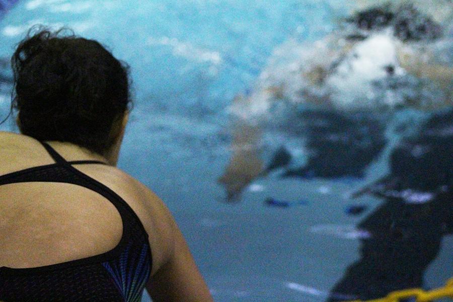 A girl's swim team member encourages her teammate to finish the race strong.  With this attitude, the team believes they can take home a win at districts.