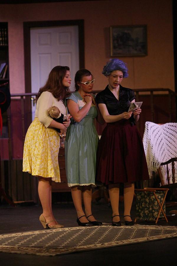 Mackenzie Morris, Rachel Fortney, and Gea Henry look at a newspaper in The Curious Savage.