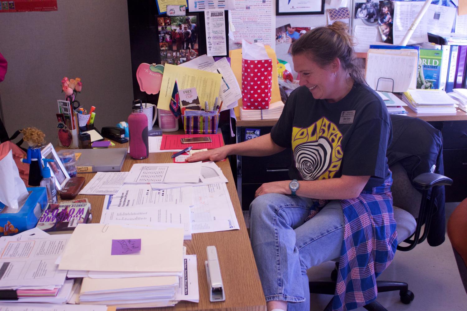 Mrs. Baize grins while getting work done at her desk. She teaches English along with sponsoring the Speech and Debate club. 