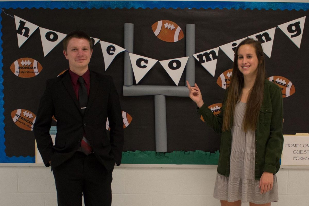 Senior Aly Janis and Junior Gabe Prather stand with FHC homecoming advertisement sign