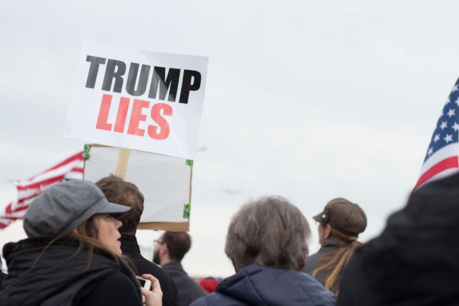 Protestors outside wield signs reading Trump Lies among other slogans. Protesters arrived before noon and remained outside until the president spoke.