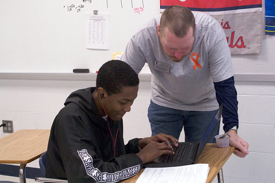 Mr. Rhorbach leans over a student to help with his assignment. He always does his best to ensure his kids understand the curriculum. 