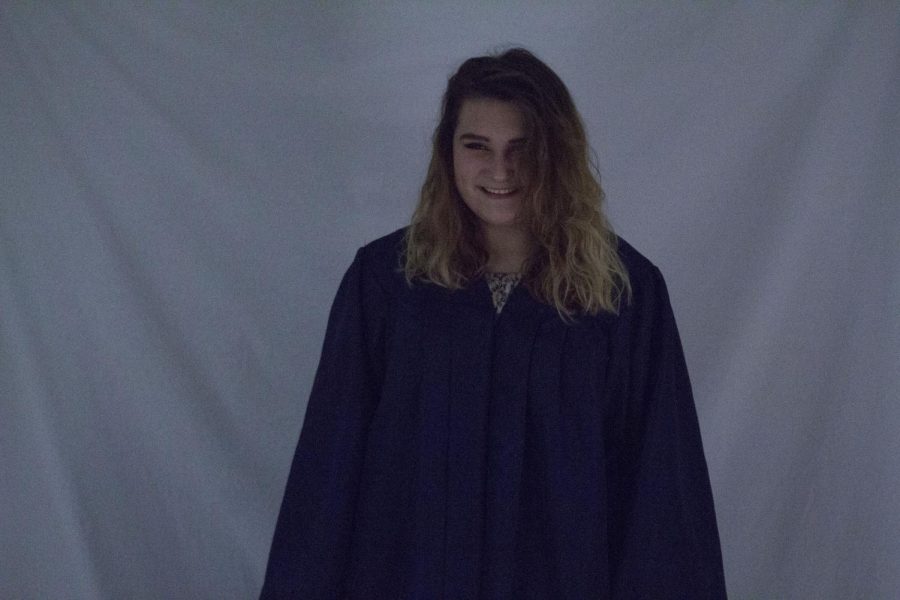 Senior Whitney Klein laughs along with friends in her graduation gown. Taken on her last day of high school, the image contains an array of emotions.