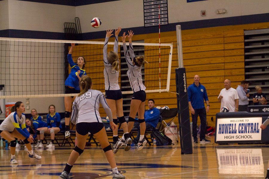 Two Spartan volleyball players block the ball.