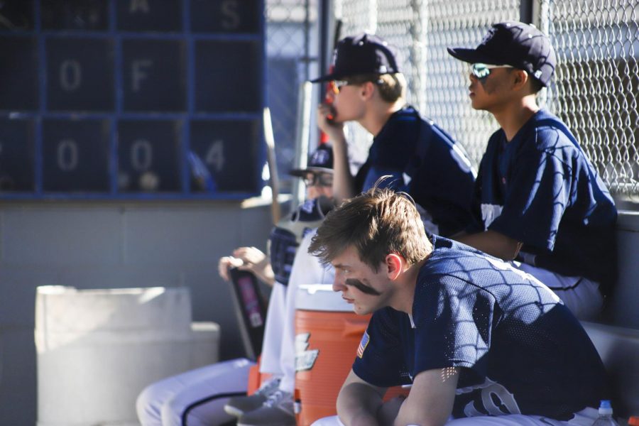 The varsity baseball players look on from the dugout.