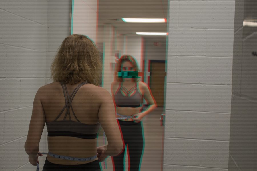 A+girl+looks+into+a+mirror%2C+measuring+her+waist.+People+affected+by+eating+disorders+often+feel+inadequate+in+their+appearance+and+turn+to+unhealthy+methods+to+become+happier+with+themselves.+
