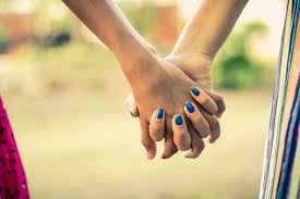 As a couple walks through the park. The two teens hold hands.