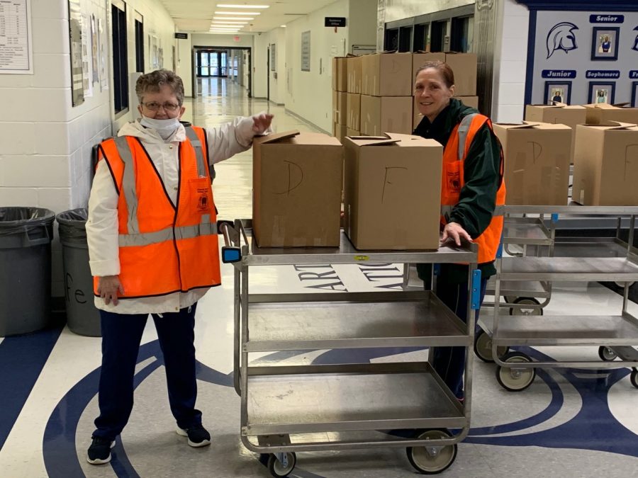 Grace Clifford and Monica Wojciehowski move pre-packed meals through the halls as part of the meal pick-up service made available to those families in need on March 24.