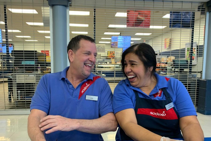 Cafe staff members Ron and Catrina laugh in the cafeteria. They aim to bring joy to students each day.