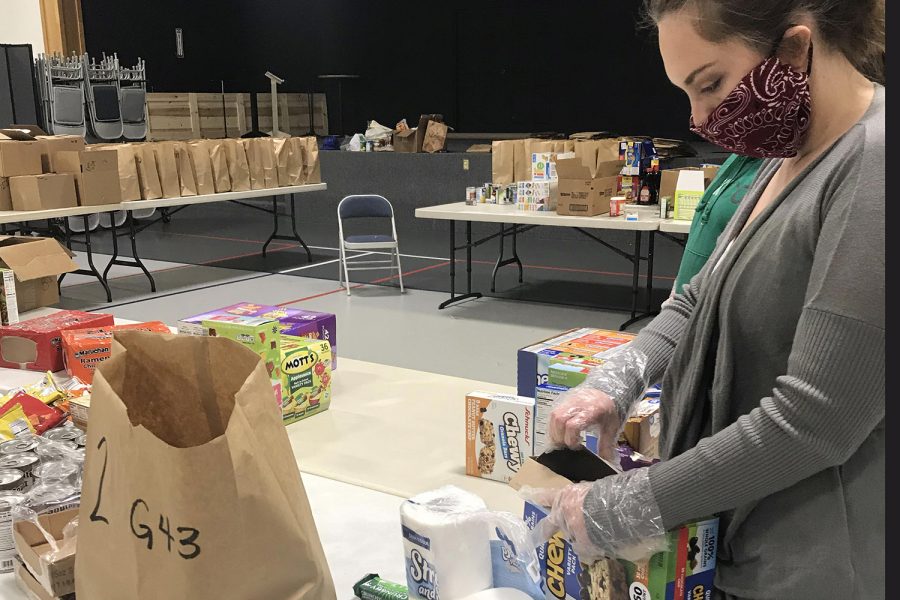 A+volunteer+is+pictured+packing+food+into+grocery+bags+to+go+to+a+vulnerable+family+through+either+a+church+or+a+school+district.+The+bags+are+packed+under+strict+conditions+%28such+as+wearing+masks+at+all+times%29+to+ensure+the+health+of+both+the+families+and+the+volunteers.