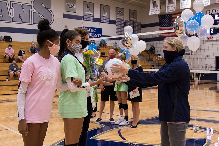 Elexus Pearson reaches out to receive a signed volleyball from Coach Gronek.