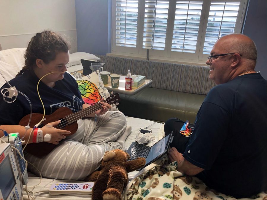 One of the ways Analiesa Hollowood passed nearly two months in the hospital was by learning some new skills. Here, she plays Somewhere Over the Rainbow, on the ukulele for her father, Jay. Photo Courtesy of Darla Hollowood 