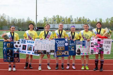 The girls soccer seniors stand with their posters during senior night.
