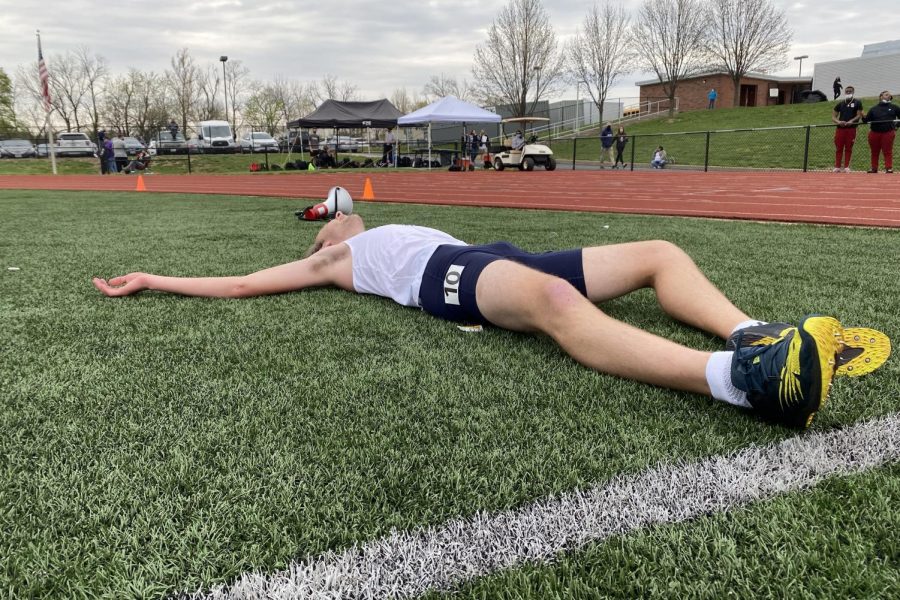 Senior Reed Easterling lays in pain after getting a personal record in the 1600 meter race.