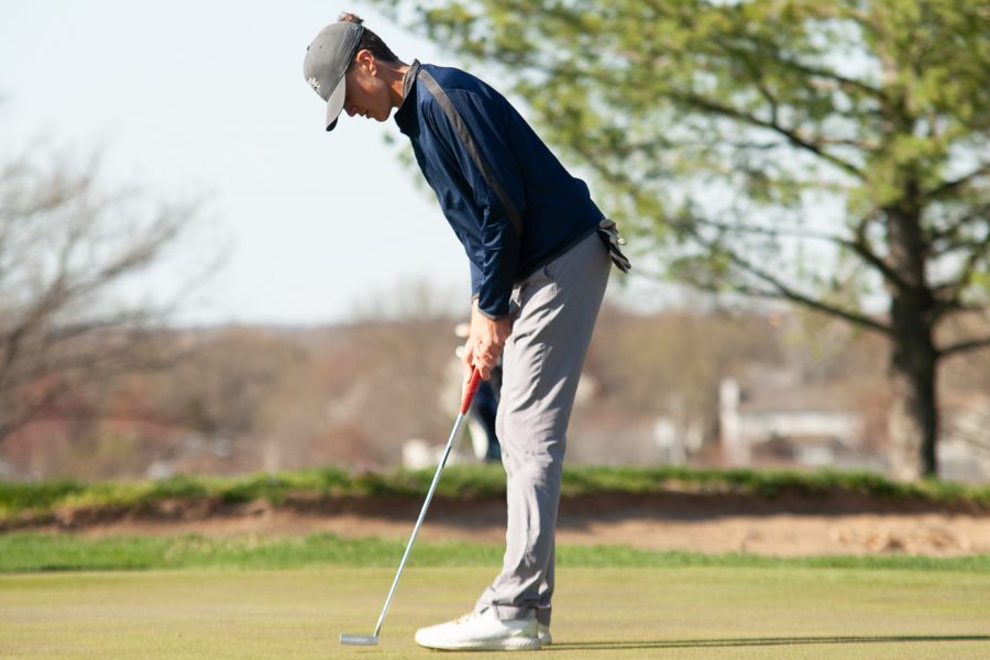 Junior Sam Emrick aligns his club up with the golf ball. He focuses as he prepares to hit the ball. 