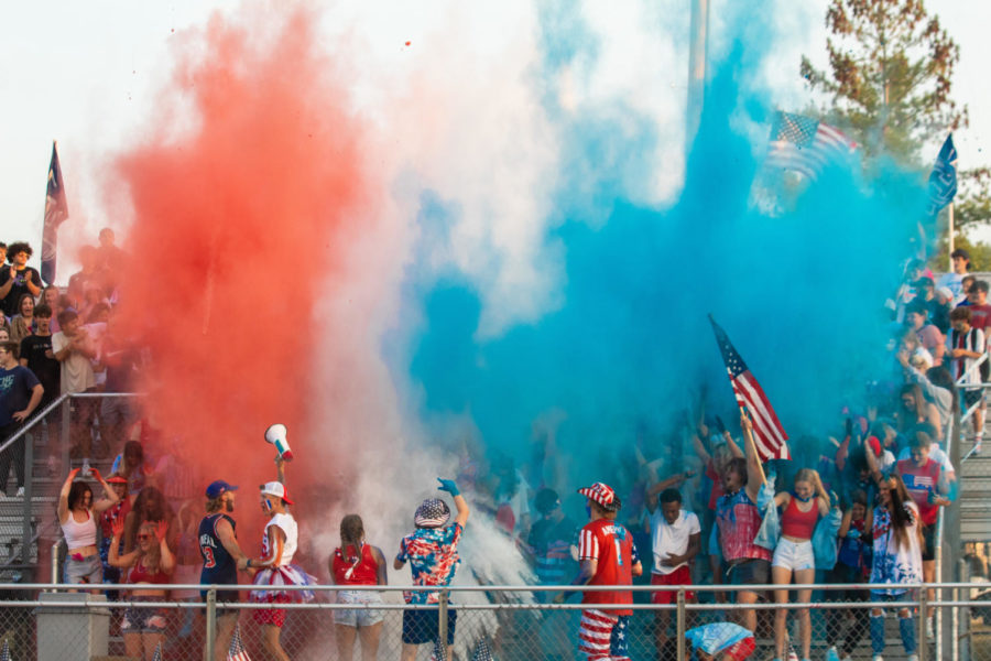 The student section throwing red white and blue powder in the air.