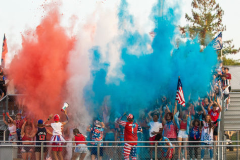  Red, white, and blue powder is thrown up into the air in the student section at the red, white, and blue themed football game. There is a newfound sense of school spirit that shines through in the student section.