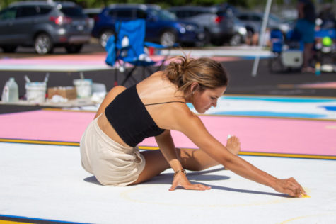 SKETCH IT OUT: Morgan Corbitt sketches in her design using a piece of yellow chalk as she  prepares to paint her spot on the parking lot.“It was super fun, but also really really stressful,” Corbitt said. 