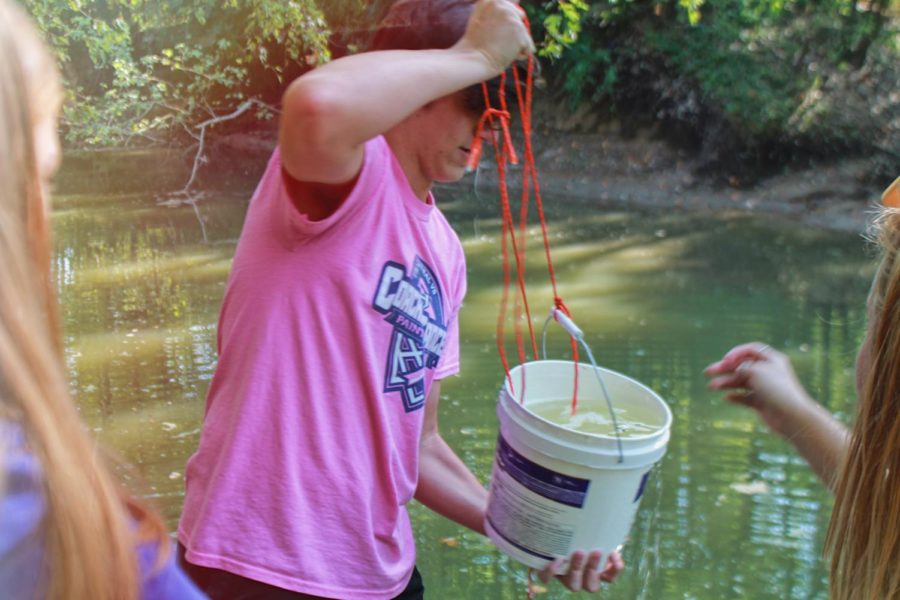 HOSA Vice President Zach Lewis holding a bucket of water from a lake. By testing water around FHC, HOSA is able to determine if there are environmental concerns around the school.