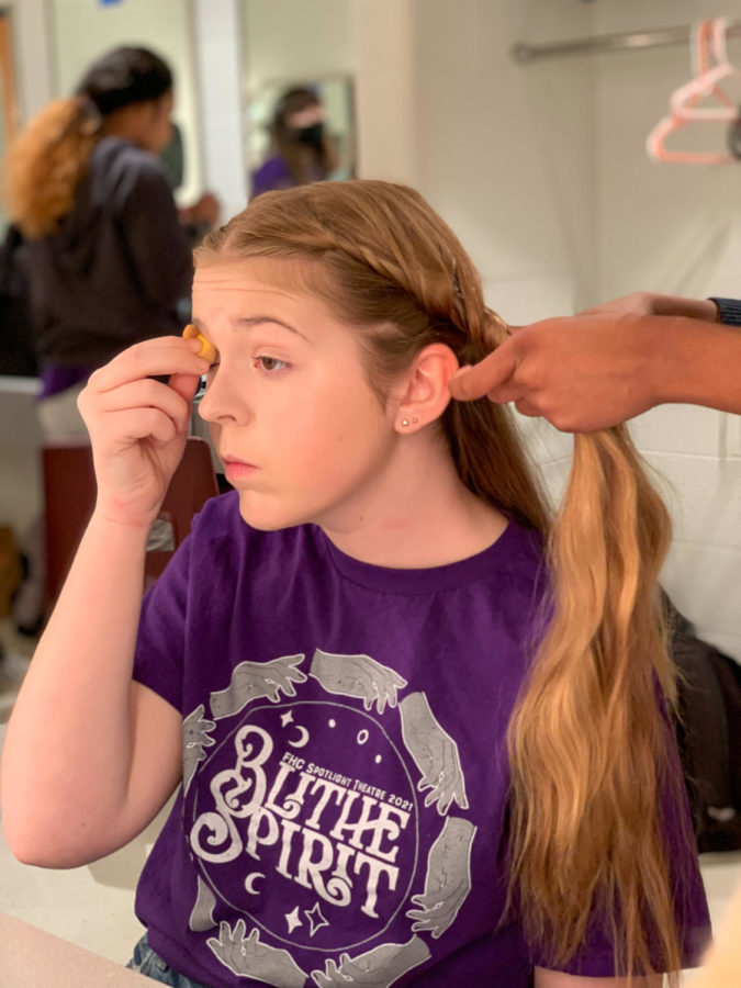 MAKEOVER TAKEOVER: As someone does her hair, Abby Meyers puts on her makeup for dress rehearsal. Putting on a show takes a lot of work from putting on makeup, dressing in costume, and getting the stage ready.