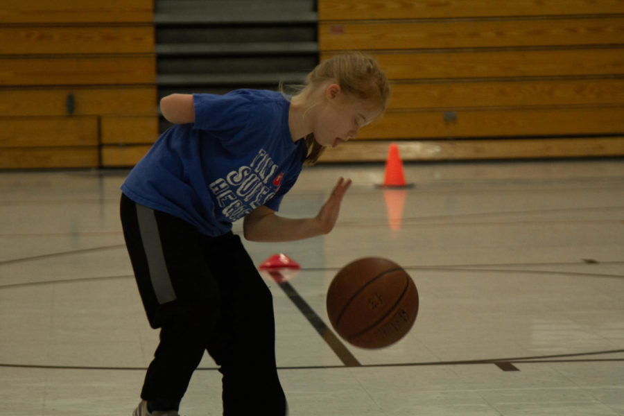 Olivia practices dribbling with one arm behind her back.