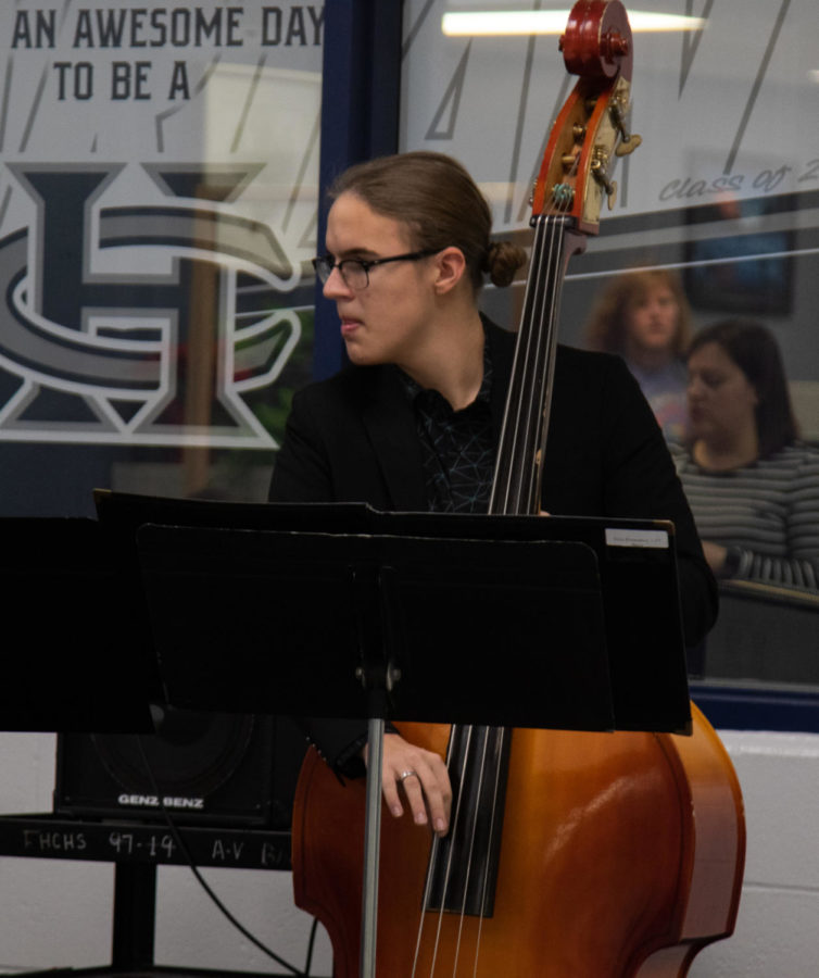 Senior Tyler Kropp reads his music while holding the cello.