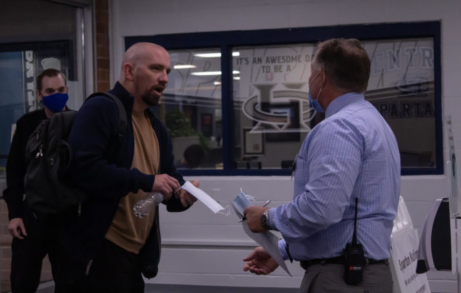 Dr. Sonny Arnel hands a mask to substitute teacher Sean Collins. All visitors, staff, and students must wear a mask when entering the building through Jan. 18. The board of education will re-evaluate the mask requirements later in January.  