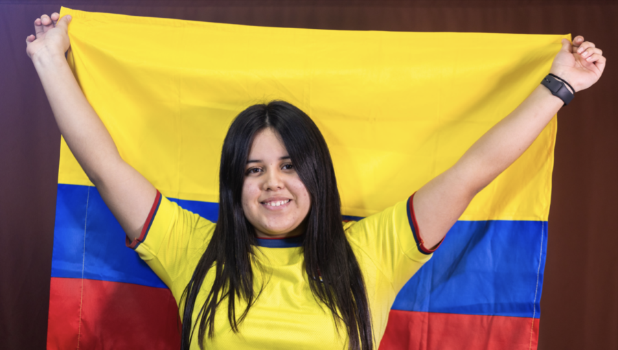 Flying her Flag: Sophomore Maria Velasquez stands smiling while holding up the Colombian flag. Valesquez and her family immigrated to the U.S. from Colom- bia when she was 13 years old. When she first moved to the United States, Valequez did not know how to speak English. Over time and with a lot work and help from those around her, she has been able to learn the new language and is thriving.