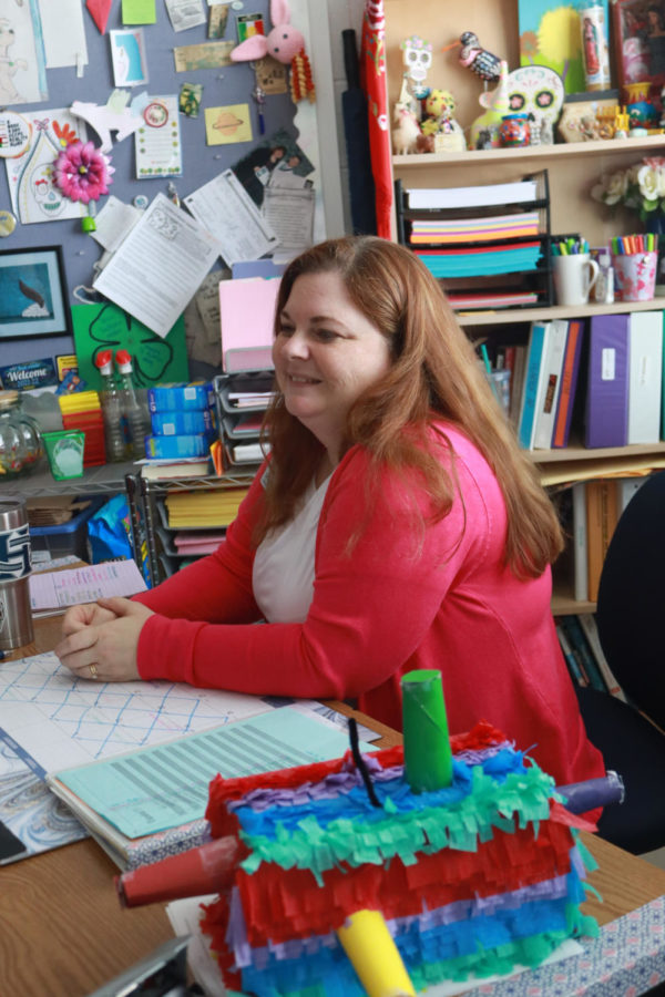 As Dr. Miller helps a student, they are surrounded by bright colors and a cheerful teacher.  Dr. Miller loves to add color and life to her classroom to make it a more enjoyable class for her students.