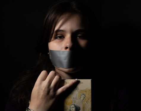 Cordelia Kraft clutches book while crying after hearing about SB 775. She duct tapes her mouth to represent the silencing that is occurring.
