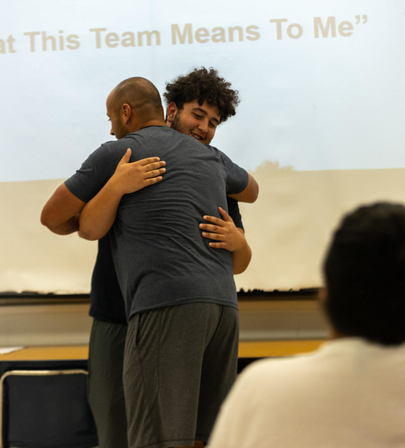 Coach Malach Radigan embraces Junior Amjaed Safi during a team meeting. Players talked about why the team matters to them.