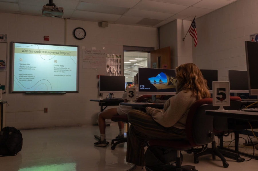 Environmental club members gather around the board in the learning common's classroom to discus how they can improve their carbon footprint. 