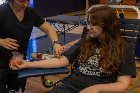 Waiting in a donation chair in the large gym, Molly McGraw donates blood for ImpactLife blood drive.