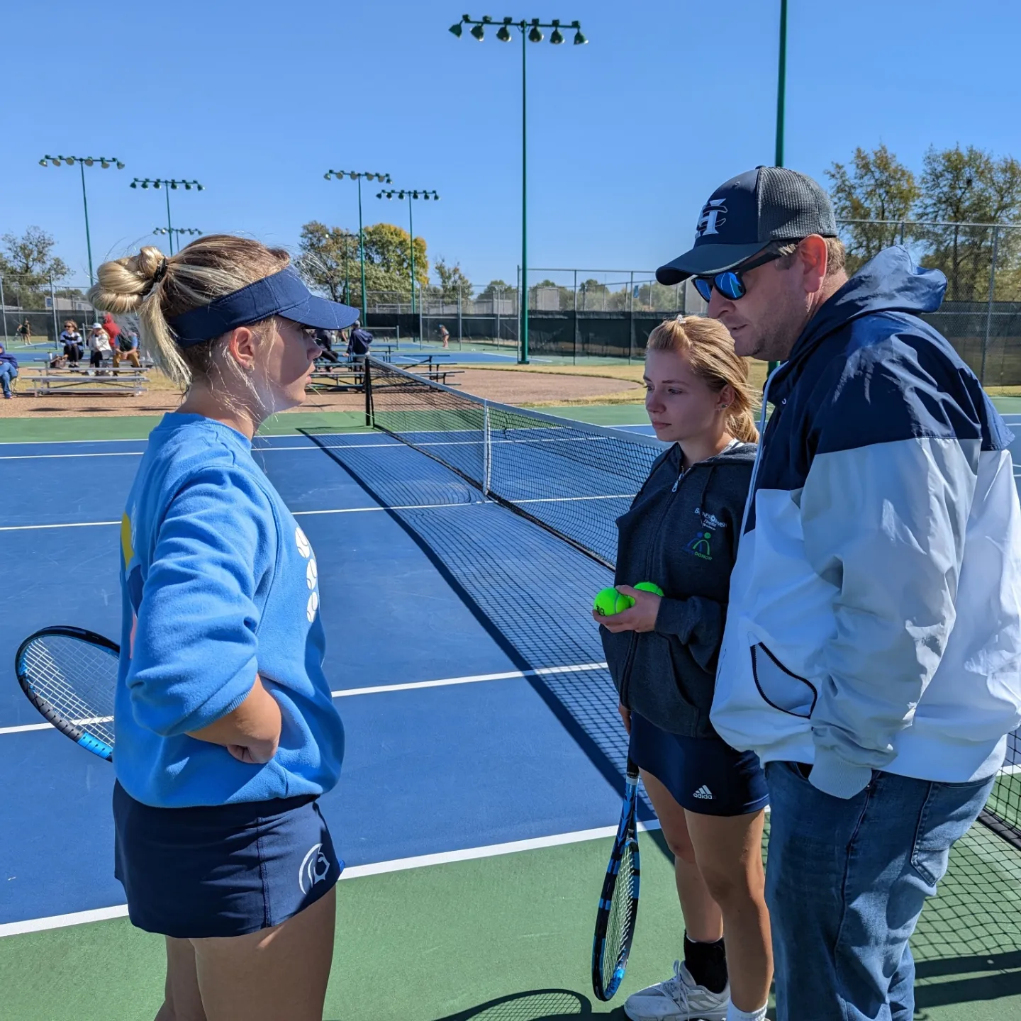 Reed gives a pep talk to seniors Katie Groat and Kate Voges at State in Springfield. Reed and Rohrbach took Groat and Voges to State on October 13. Photo by FHC Tennis @FHCTennisFam 