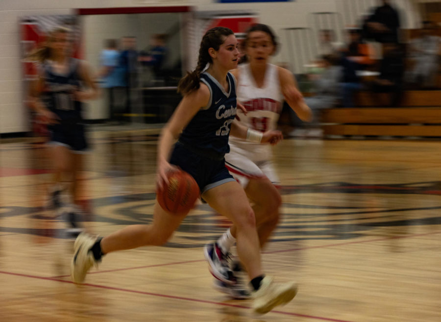 A player dashes by as she dribbles toward the hoop in hopes of scoring another point before the timer runs out. 