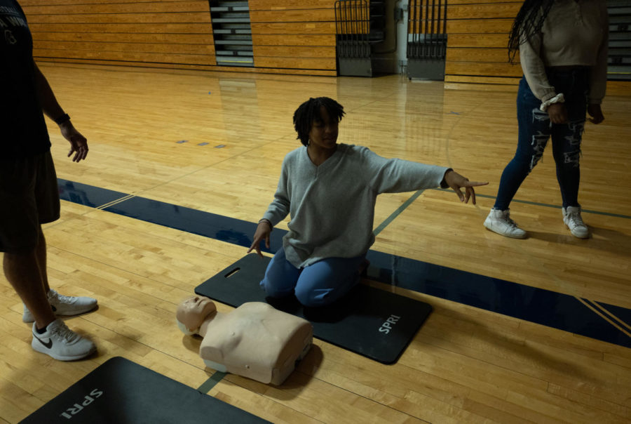 A senior kneels on a mat ready to practice chest compressions. During the training, Students were shown how to perform CPR, but in order to pass they needed to show with Coach Malach Radigan or Coach Andrew Carter they could complete the action steps. 