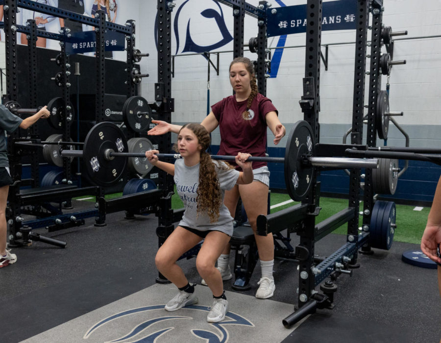Senior+Gianna+Bruenning+assists+an+underclassman+with+her+squat+rep.+Teammate+Delaynie+Brown+mentioned+how+winter+workouts+are+a+glimpse+into+the+future+of+their+team.+Were...getting+a+look+at+what+our+program+is+gonna+look+like+that+year.