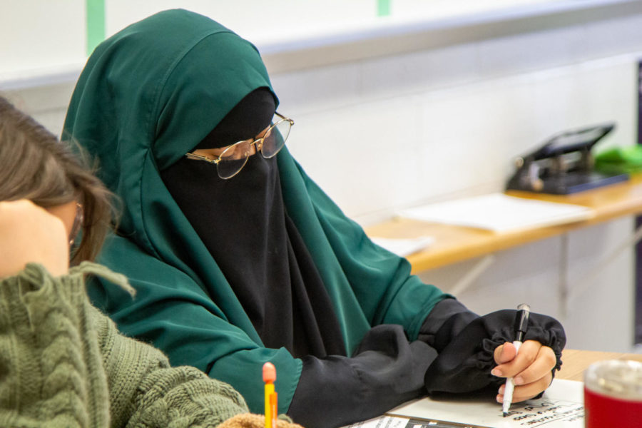 Working in class among her peers on a whiteboard, sophomore Jessica Ayres has experienced backlash at school from her choice to veil, but she finds sanctuary in veiling. "I find it very liberating actually, [veiling] makes me feel better about myself," Ayres said. 