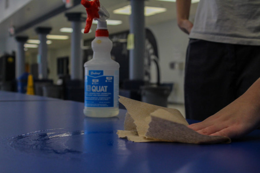 A student wiping down the cafeteria tables. Due to the shortage in custodians, students have been hired to fill in the gaps.