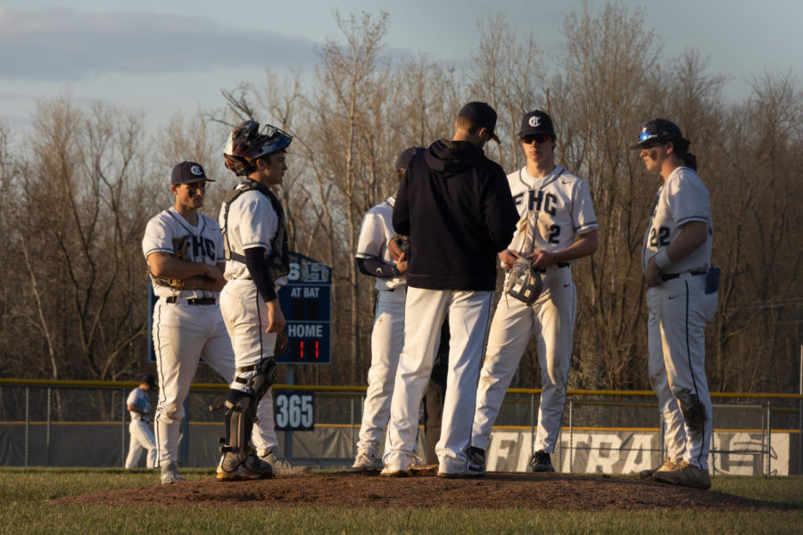 Conferring with his team on the mound, Coach Nick Beckmann discusses strategy during the baseball teams 13-9 loss to Vianney on March 27.
