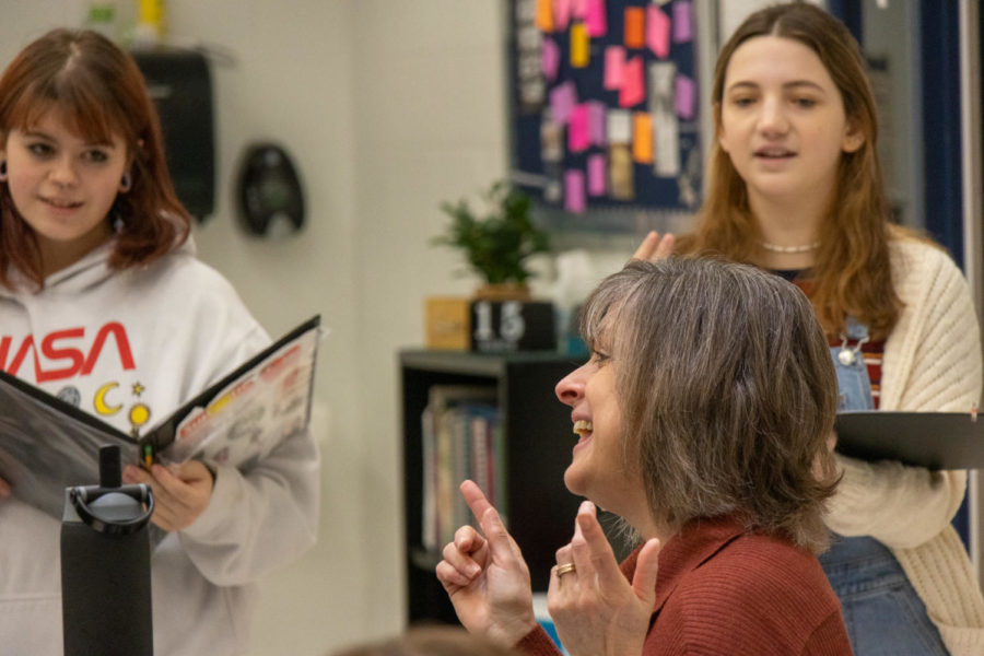 Smiling at the piano with her Treble Choir students, Mrs. Donna Solverud leads her students in song. 