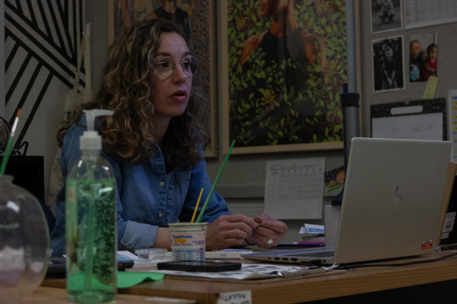 Peering over her laptop, art teacher Megan Clayton talks to a student in her second hour class.