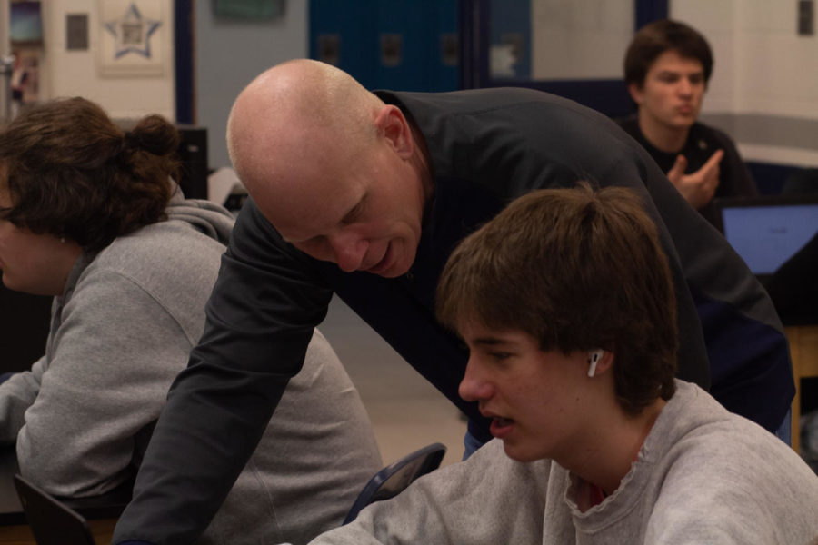 Physics teacher Ryan McCoy leans in to check a students work in his AP Physics class. 