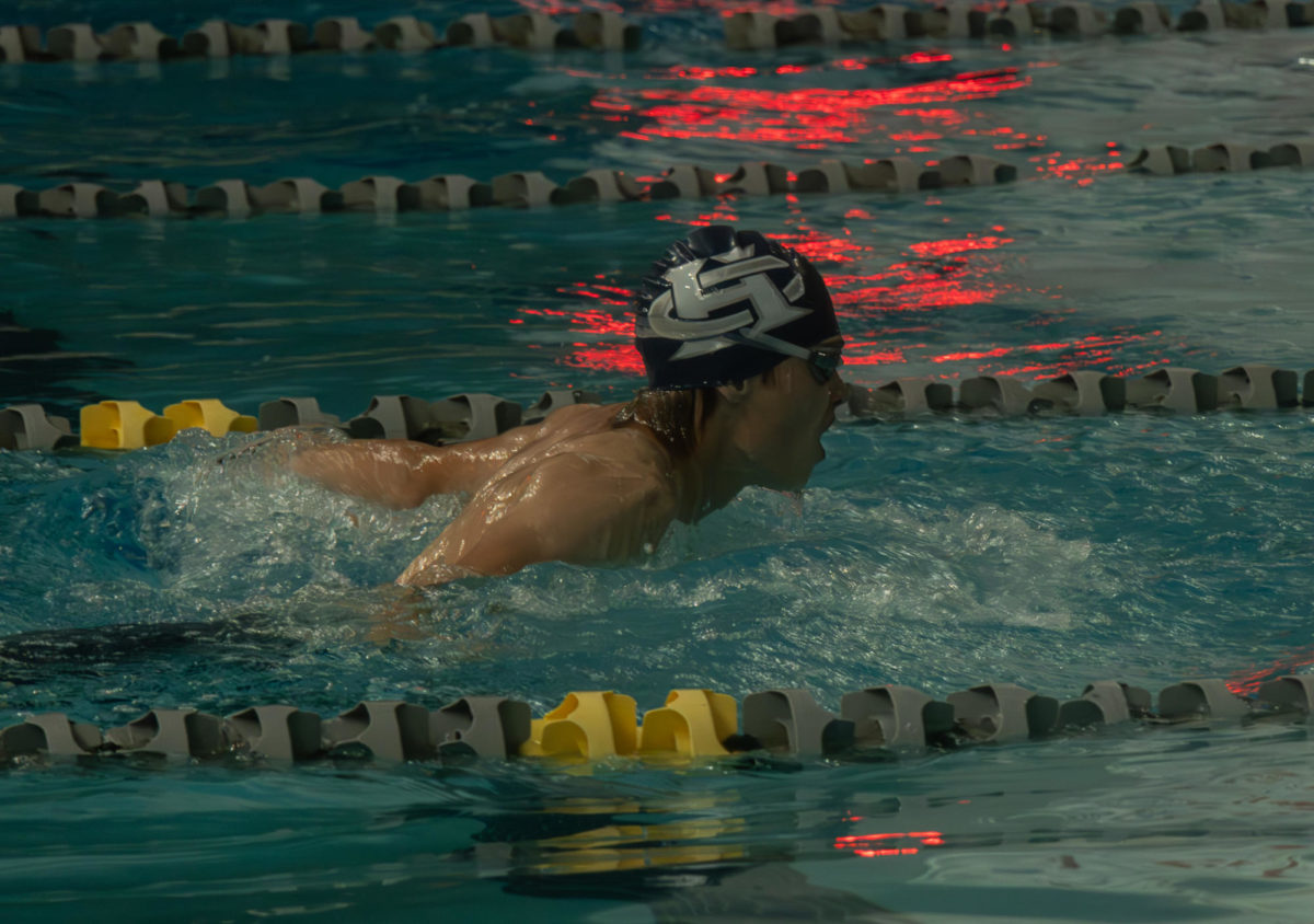Junior Connor Casey swims towards the end of the lane in hopes of beating his opponents.