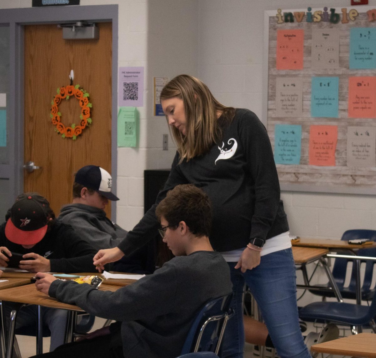 Mrs. Brittany Williams leans over as she shows a freshman student what the question is looking for.