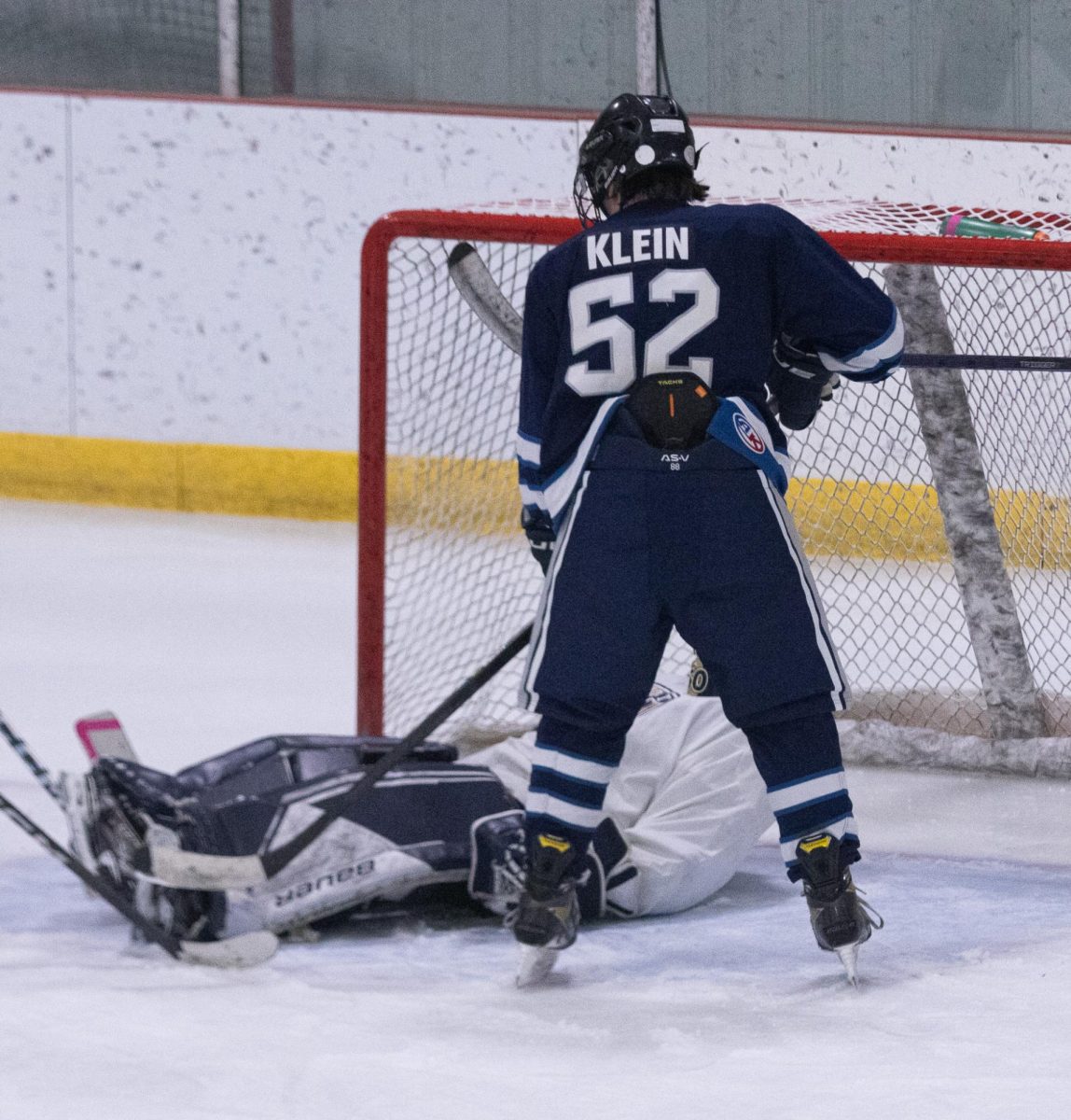 Fisher Klein nudges his stick at the goalie, hoping to drop the puck in. 