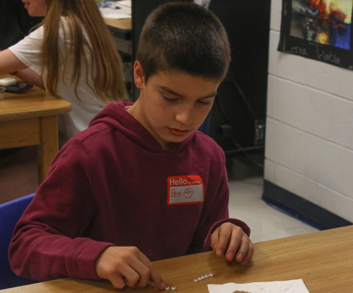 The middle school student picks out letters to put on his friendship bracelet. 