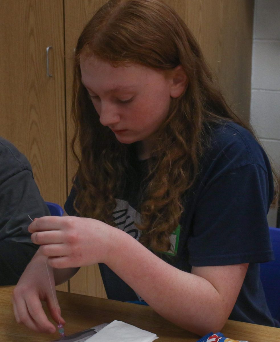 The middle school student measuring her friendship bracelet string.