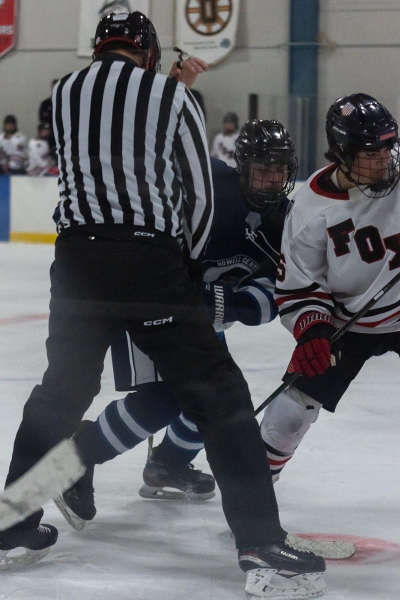 A player skates around the ref, racing towards the puck.